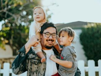 man in white shirt carrying girl in gray shirt