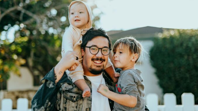 man in white shirt carrying girl in gray shirt